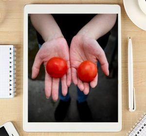 Laptop with hands holding tomatoes