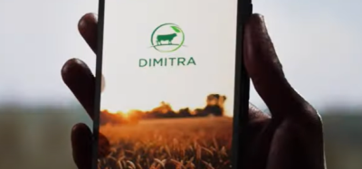 A farmers hand holds a mobile phone displaying the Dimitra Connected Farmer App