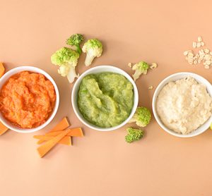 Bowls with healthy baby food on color background