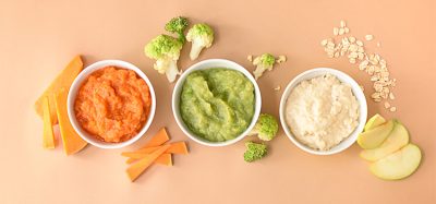 Bowls with healthy baby food on color background