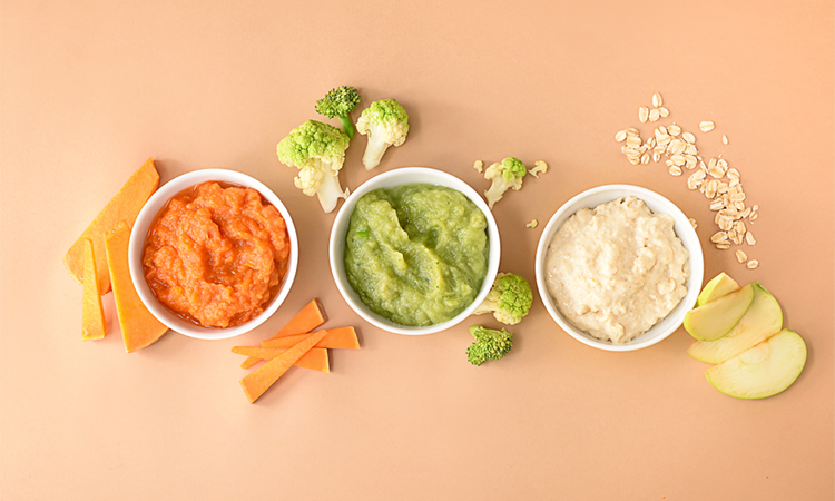 Bowls with healthy baby food on color background