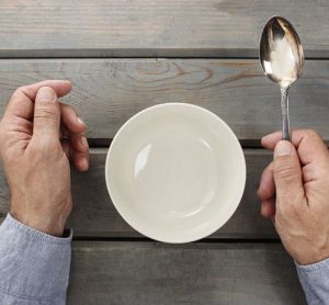 Hungry man waiting for his meal over empty bowl on wooden table.