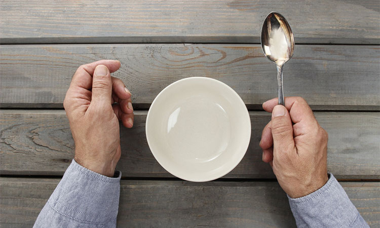 Hungry man waiting for his meal over empty bowl on wooden table.