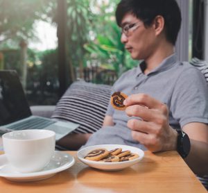 man eating biscuits at computer