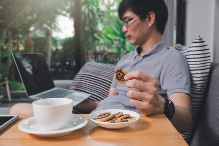 man eating biscuits at computer