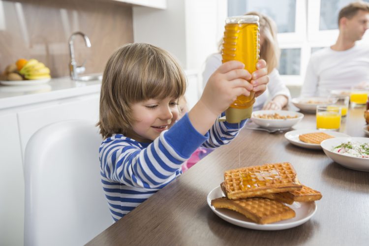 squeezing honey onto waffles