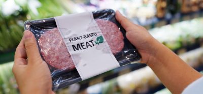 hands holding plant based burgers