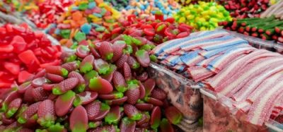 An assortment of colorful candies at a market stall, showing vivid artificial dyes soon to be banned by FDA regulation. Great visual for clean label and natural food trends.