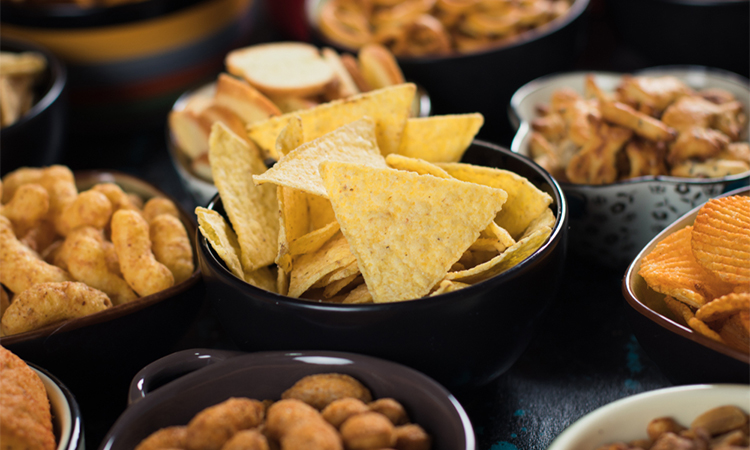 Salty snack including peanuts, potato chips and pretzels served as party food in bowls